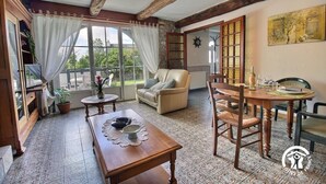 A cozy room with a wooden table, a sofa, and a dining table set for two. - Pont Bihan - CARNAC - Gîte (CARNAC)