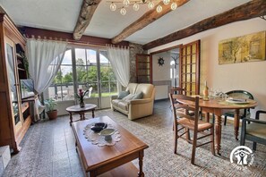 A cozy room with a wooden table, a sofa, and a dining table set for two. - Pont Bihan - CARNAC - Gîte (CARNAC)