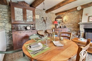 A rustic dining room with a stone wall, wooden furniture, and a fireplace. - Pont Bihan - CARNAC - Gîte (CARNAC)
