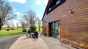 A wooden building with a patio area featuring outdoor furniture.