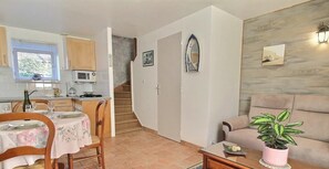 Uma área de refeições com uma mesa posta para dois, uma cozinha equipada com micro-ondas e uma escada que dá para outro andar.