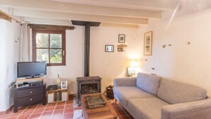 Ein gemütliches Wohnzimmer mit Fernseher, Kamin, einer Couch und einem kleinen Tisch.