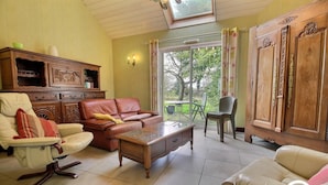 Una sala de estar con sofá, sillón y aparador de madera.