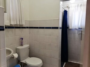 A small bathroom with a toilet, sink, and shower curtain. - Boathouse Bed and Biscuit - Cabin (Margate)