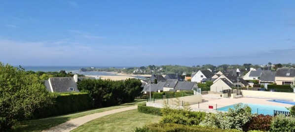 A residential area with houses, a swimming pool, and a view of the sea.