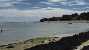 Ein Strand mit felsigem Ufer, ruhigem Wasser und einigen Booten.