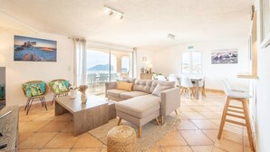 A spacious living area with a sofa set, a dining table, and chairs. There are large windows providing a view of the outdoors. - Villa la Cagne (Saint-Raphaël)