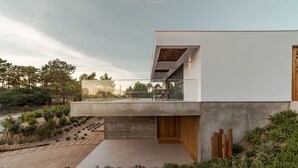 A modern building with a flat roof, a concrete facade, and a wooden deck.
