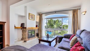 A living room with a fireplace, a sofa, a coffee table, and a view of the outdoors.