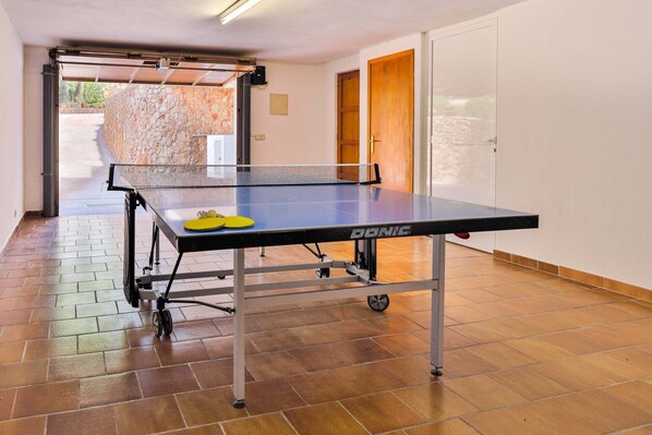 A ping pong table in a room with a tiled floor and a stone wall. - Egos 89 holiday home for 10 people, seafront position with direct beach access. (Cala D'or)