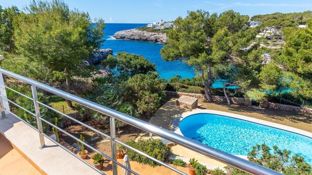 A pool area with a view of the sea and surrounding trees.