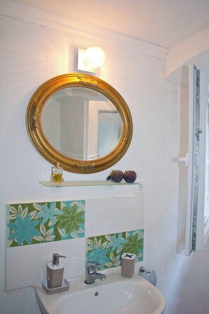 A bathroom with a round mirror, a sink, and decorative tiles.