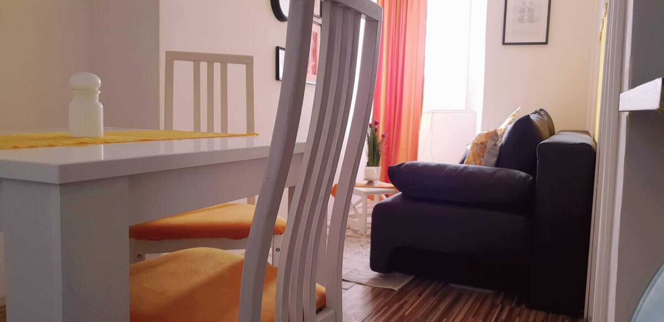 Una sala de estar con un sofá azul oscuro, una mesita y una silla.