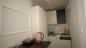 A compact kitchen with white cabinets, a black countertop, a pink kettle, and a pair of glasses on the counter. - Apartment in Center Old Town (Dubrovnik)