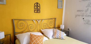 A bed with a metal headboard, two pillows, a wall with a decorative metal piece, and a wall with a motivational quote.