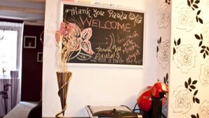 A blackboard with a welcome message, a vase with dried flowers, a notebook, and a red telephone on a desk. - Apartment in Center Old Town (Dubrovnik)