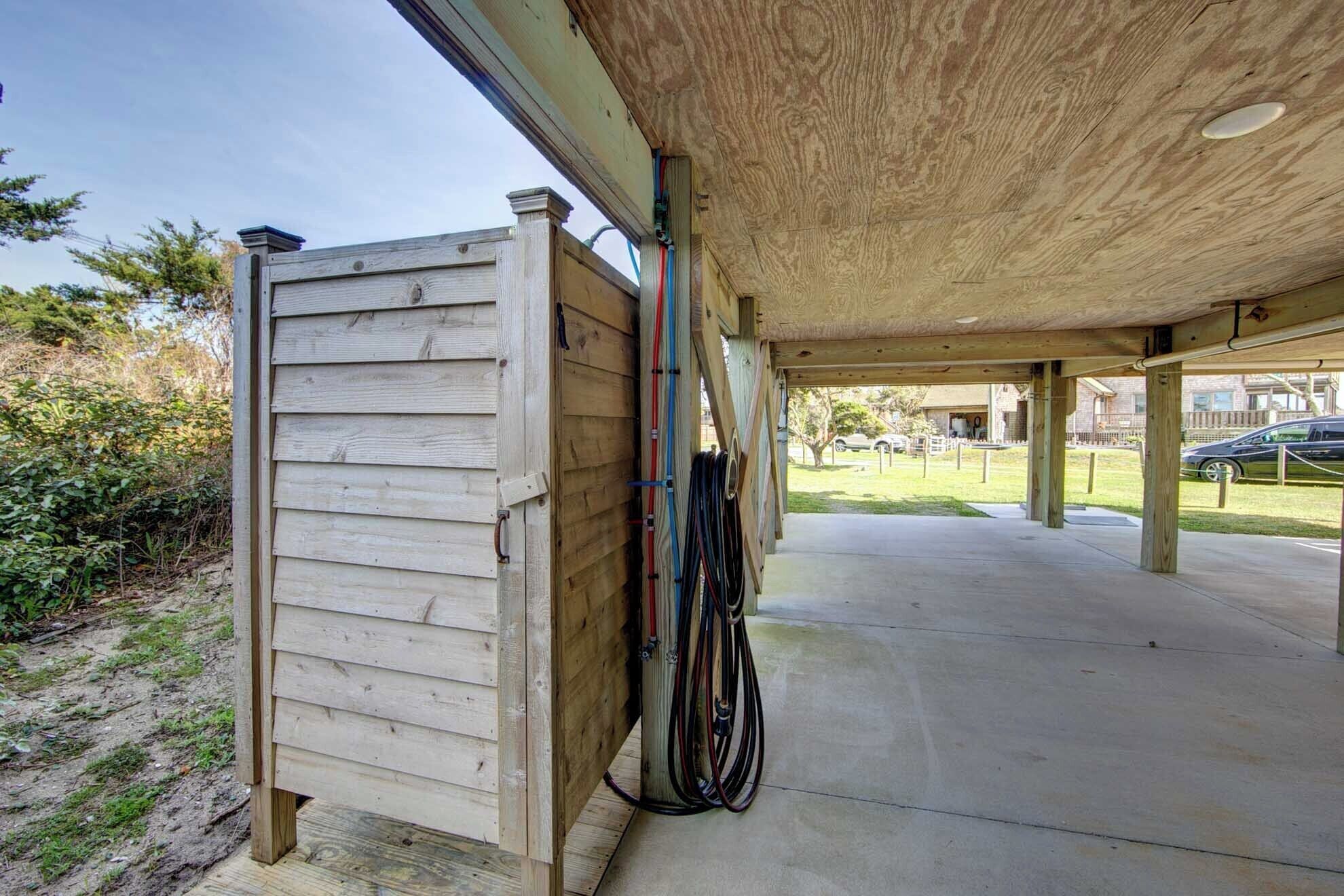 A covered outdoor area with a wooden structure, possibly a shed or storage unit, and a concrete floor.