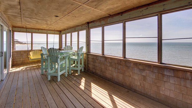 A covered deck with a view of the sea, featuring a table and chairs. - Shore Enuf - Ocracoke Island (Ocracoke)