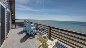 A balcony with a view of the ocean, featuring two chairs and a table. - Shore Enuf - Ocracoke Island (Ocracoke)