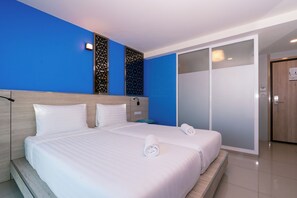 A hotel room with two beds, a blue accent wall, and a sliding door closet. - One Budget Hotel Chiang Rai Airport (Chiang Rai)