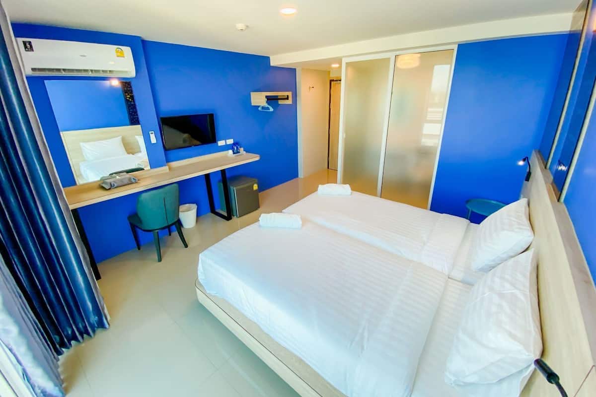 Una habitación de hotel con cama, escritorio, silla, televisor y puertas correderas.