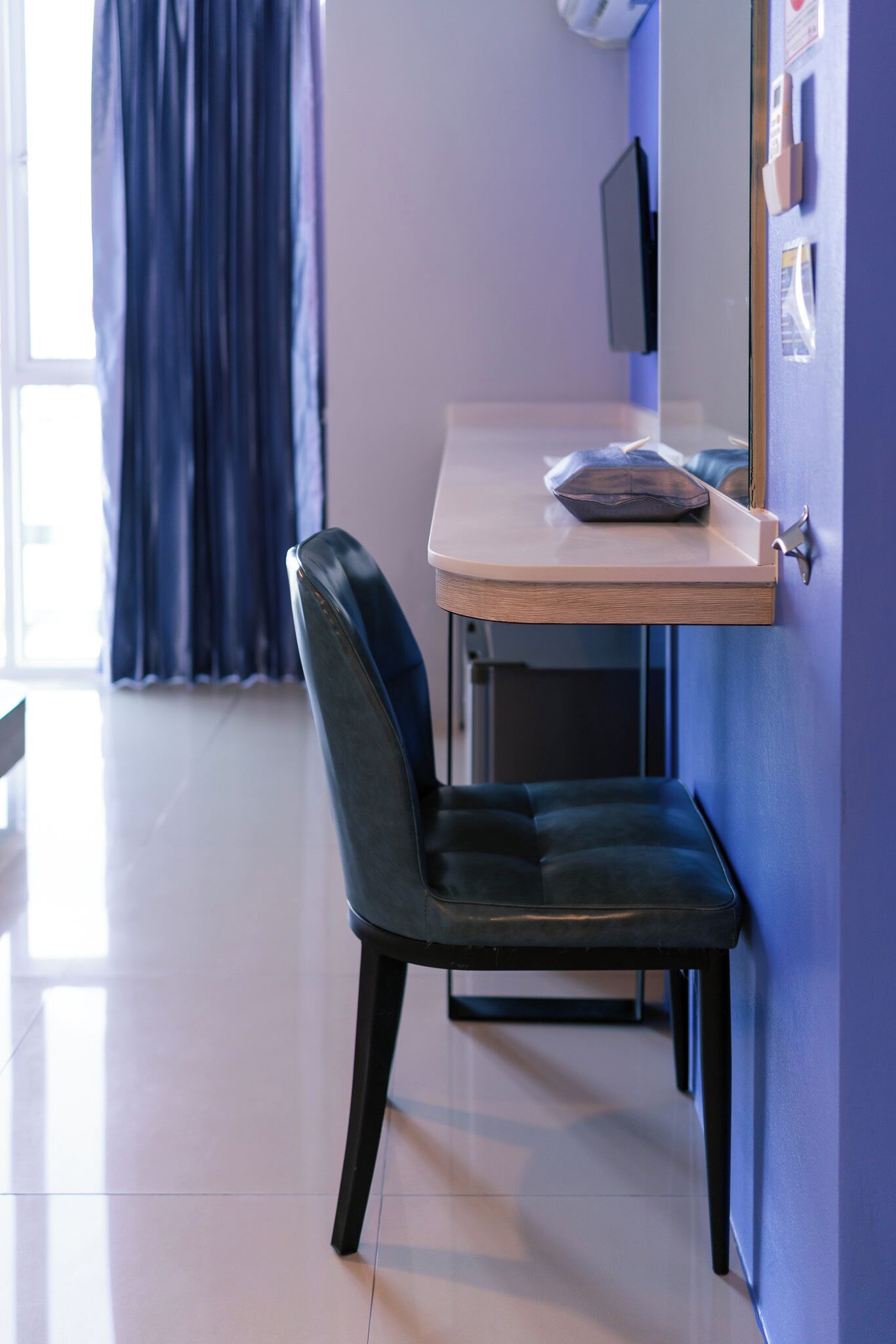Una habitación moderna con escritorio, silla y pared azul.