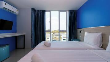 Ein Hotelzimmer mit Bett, Schreibtisch, Fernseher und Blick auf die Stadt.