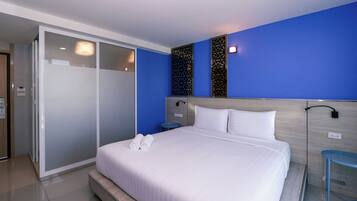 A modern hotel room with a large bed, a walk-in closet, and a blue accent wall.