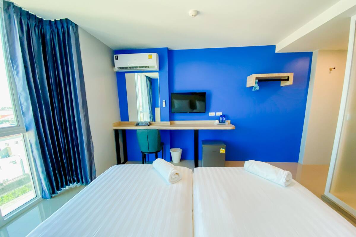 Una habitación de hotel con dos camas, un escritorio, un televisor y un equipo de aire acondicionado.