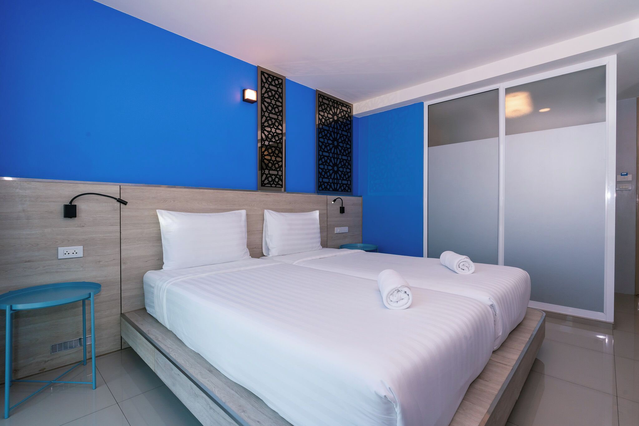 Habitación de hotel con una cama grande, una mesita de noche, un armario y un panel decorativo en la pared.