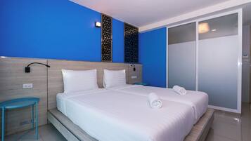 Habitación de hotel con una cama grande, una mesita de noche, un armario y un panel decorativo en la pared.