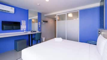 Een hotelkamer met een bed, bureau, stoel, televisie en een kledingkast.