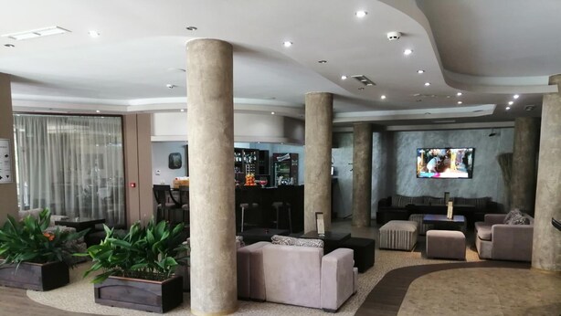Un vestíbulo amplio con techos altos, grandes pilares y una zona de bar.