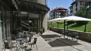 Un patio exterior con suelo de piedra, mobiliario para exteriores y vista de un edificio al fondo.