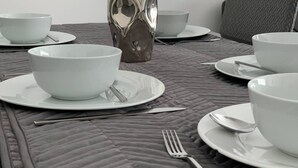 A dining table set with white bowls, plates, and cutlery, a silver vase, and a grey upholstered chair. - Large 5 Bed House / Wolverhampton + Parking (Wolverhampton)