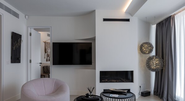 A modern living room with a flat-screen TV, a fireplace, and a round coffee table.