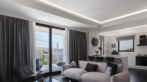 Una sala de estar moderna con un sofá, una mesa de centro y vistas de la ciudad a través de amplios ventanales.