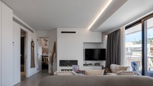 Una habitación de hotel moderna con una cama grande, televisión de pantalla plana, chimenea y balcón con vistas.