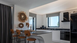 Una cocina moderna con una isla central, taburetes de bar, horno empotrado y un ventanal grande.