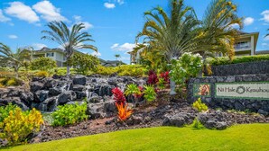 A tropical resort with a waterfall, lush greenery, and a sign reading "Na Hale Keauhou".