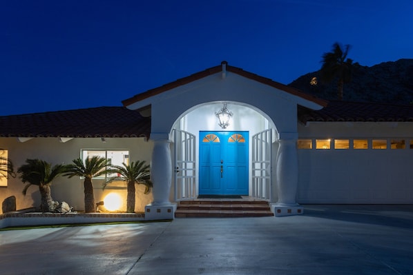 Uma casa com porta azul, colunas brancas e telhado em telhas.