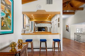 Cozinha com teto de madeira, área de bar com banquetas e uma janela grande.