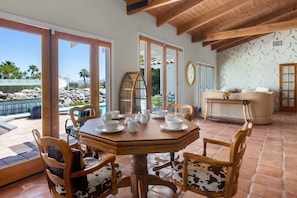 A dining area with a round table, chairs, and a view of the outdoors. - Paradise Splash at Little Tuscany – Luxe Pool Retreat (Palm Springs)
