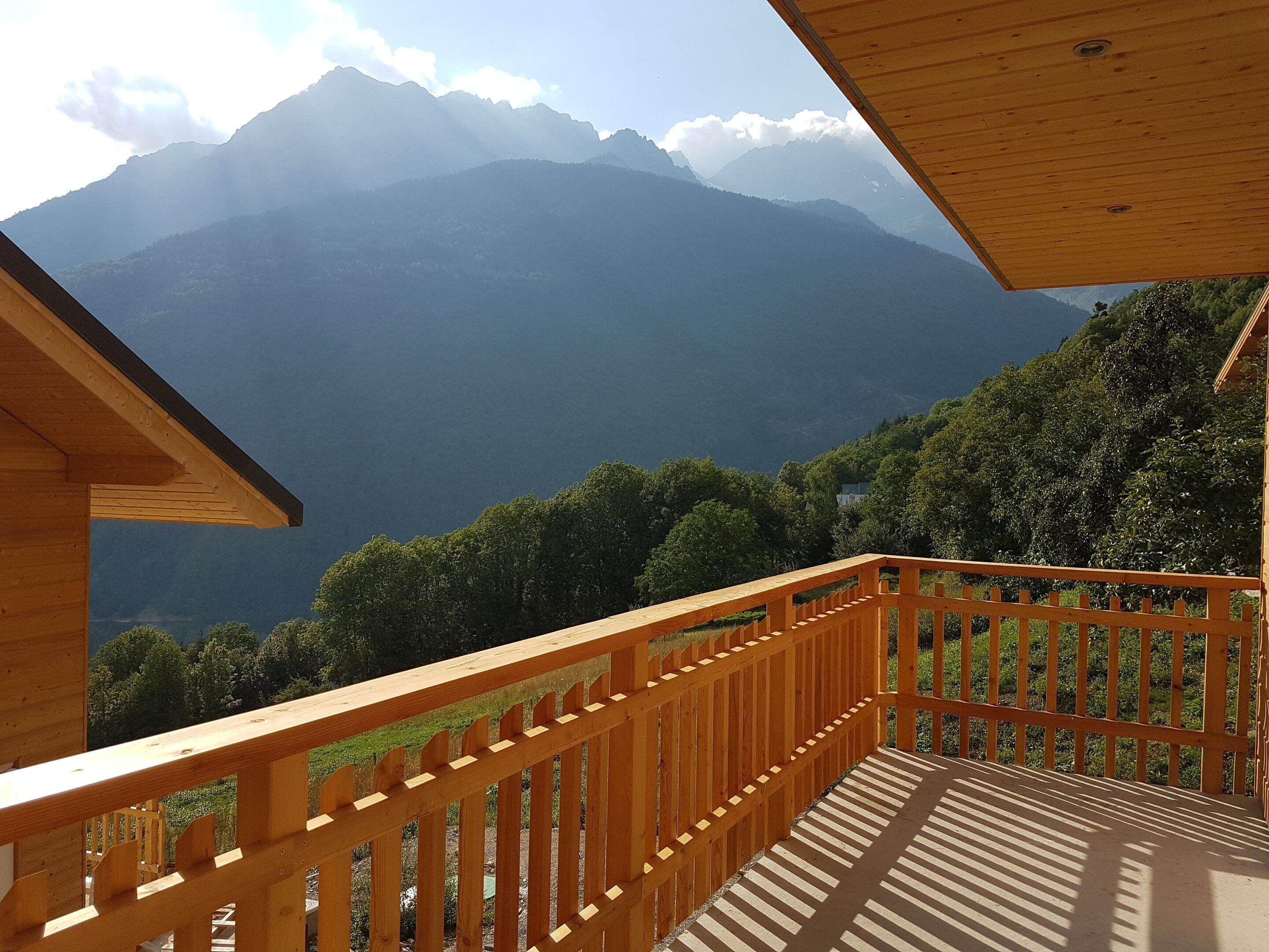 A wooden balcony with a view of a mountain range.