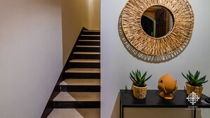 A staircase with a black railing and a wall-mounted mirror with a woven frame.