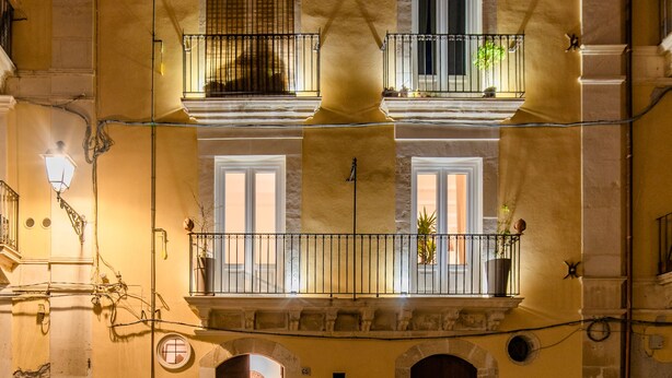 A multi-story building with balconies, a street lamp, and a door.