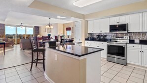 A modern kitchen with white cabinets, a large island, and stainless steel appliances. - Yacht Club Villas #1-1005 Beautiful Waterfront Villa in Barefoot Resort! (North Myrtle Beach)