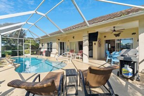 A covered outdoor swimming pool with lounge chairs, a grill, and a view of the surrounding landscape. - Poolside Bliss and a Family-Friendly Oasis (Naples)