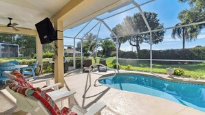 A covered outdoor pool area with lounge chairs, a pool ladder, and a view of the surrounding landscape. - Poolside Bliss and a Family-Friendly Oasis (Naples)
