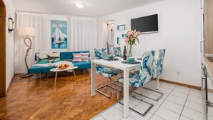 Un espace de vie compact comprenant un canapé, une table à manger et un téléviseur fixé au mur.